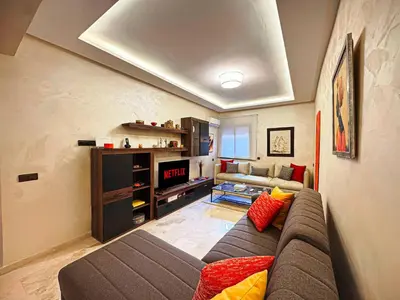 a living room with a couch and a tv at Le Nid de l'Hivernage - Piscine et Confort Moderne in Marrakech