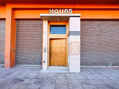 an orange building with two garage doors and a brown door at Le Nid de l'Hivernage - Piscine et Confort Moderne in Marrakech