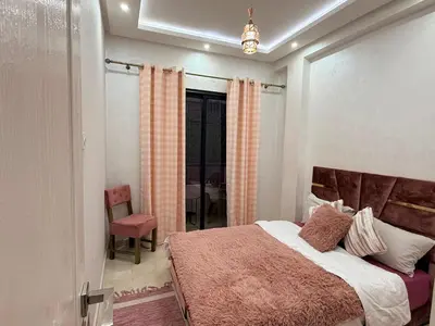 a bedroom with a large bed and a chair at Appartement Cosy and Calme Proche Centre Marrakech in Marrakech