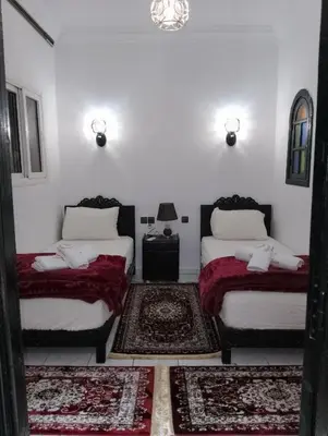 a room with two beds and two rugs at Riad Alhana in Marrakech