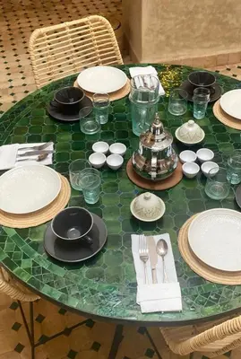 a green glass table with plates and silverware on it at Welcome to Riad Mariam & Maïwenn! in Marrakech