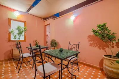 two tables and chairs in a room with plants at Riad ZEROUAL in Marrakech