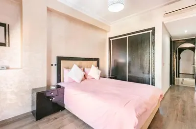 a bedroom with a large bed with pink sheets and pillows at Un super jolie appartement à gueliz in Marrakech