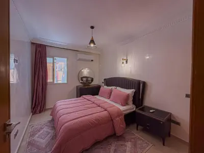 a bedroom with a bed with pink sheets and a mirror at Essalmi Luxury Apartment Gueliz in Marrakech