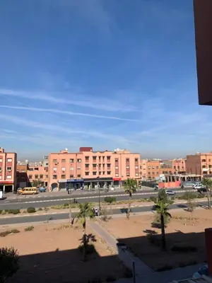 a parking lot with palm trees in front of a large building at New Apart Marrakech 2 BR-5 MN from airport in Marrakech