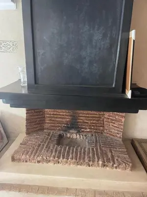 a brick fireplace with a black top on top of it at Séjours villa riad pour familles in Marrakech