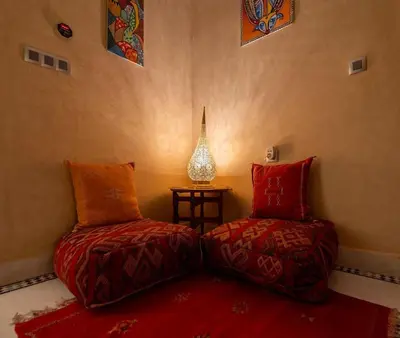 two beds in a room with a table and a lamp at Villa Sophia in Marrakech