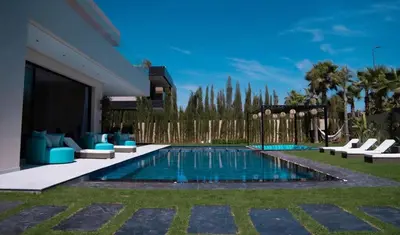 a swimming pool with chairs and a house at Villa California in Marrakech