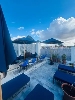 a patio with blue chairs and umbrellas on a roof at Riad Blue Berry in Marrakech