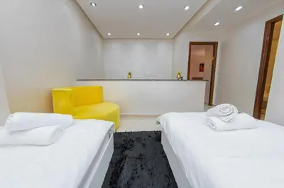 a room with two beds and a yellow chair at Duplex familiale au centee du Marrakech in Marrakech