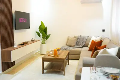 a living room with a couch and a tv at Appartement Moderne & Cosy Proche Centre Piscine, Wi-Fi Haut Débit & Netflix Marrakech in Marrakech
