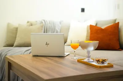 a coffee table with a laptop and a glass of orange juice at Appartement Moderne & Cosy Proche Centre Piscine, Wi-Fi Haut Débit & Netflix Marrakech in Marrakech