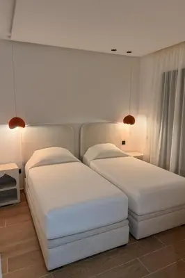 two beds in a bedroom with white walls and lights at Aube d hivernage Marrakech in Marrakech