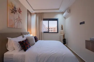 a bedroom with a white bed with a window at Appartement Chic M Avenue, Balcon, Piscine, Parking Wi-Fi Haut Débit Marrakech in Marrakech