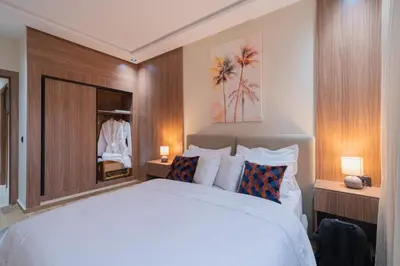 a bedroom with a large white bed and a mirror at Appartement Chic M Avenue, Balcon, Piscine, Parking Wi-Fi Haut Débit Marrakech in Marrakech