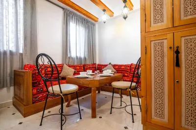 a dining room with a table and chairs and a couch at Appartement Luxe et Prestige, calme avec piscine in Marrakech