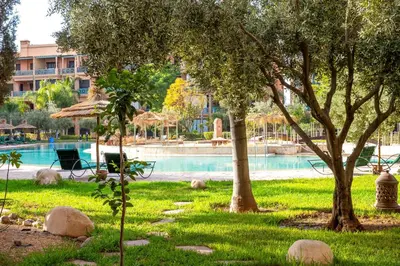 a swimming pool with trees and a building in the background at Appartement Luxe et Prestige, calme avec piscine in Marrakech