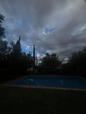 a blue swimming pool with trees in the background at Marrakech Luxury Escape Full Villa Pool & Garden in Sraghna