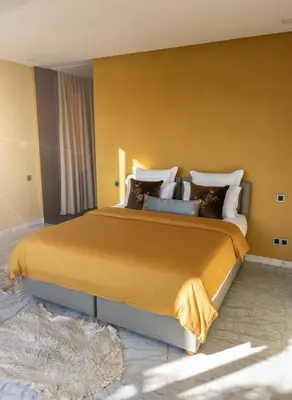 a bedroom with a large bed with yellow walls at Villa Oasis de Verre - Atlas Golf & Pool in Marrakech