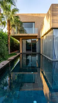 a house with a swimming pool next to a palm tree at Villa Oasis de Verre - Atlas Golf & Pool in Marrakech