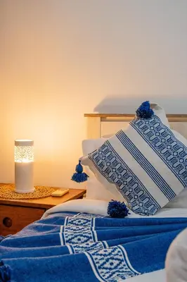 a bed with blue and white pillows and a candle at 1-Bedroom Apartment in Guéliz Center , 10 Min Jemaa El-Fna in Marrakech