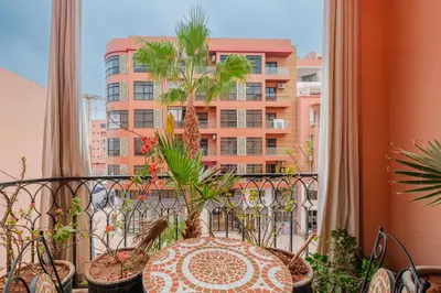 a balcony with a table and potted plants and a building at 1-Bedroom Apartment in Guéliz Center , 10 Min Jemaa El-Fna in Marrakech