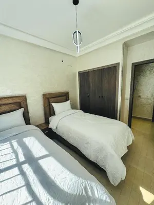 a bedroom with two beds and a pendant light at Al Waha Prestige Apartment in Marrakech