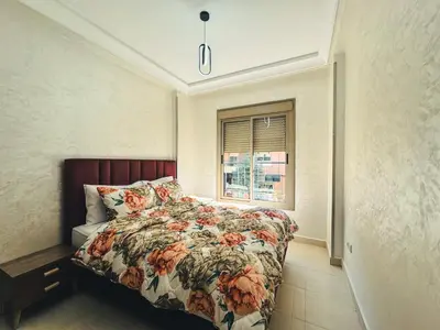 a bedroom with a bed with a floral comforter and a window at Al Waha Prestige Apartment in Marrakech