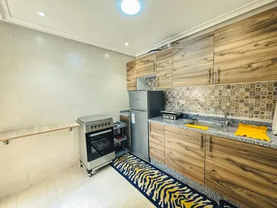 a kitchen with wooden cabinets and a stove top oven at Al Waha Prestige Apartment in Marrakech