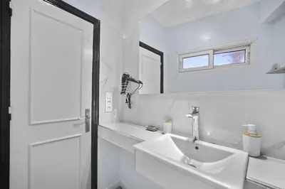 a white bathroom with a sink and a mirror at Centre Town Cozy Apartment with Panoramic View in Marrakech