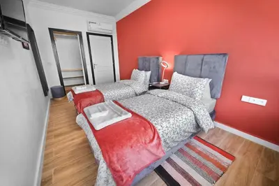 a bedroom with two beds and a red wall at Centre Town Cozy Apartment with Panoramic View in Marrakech