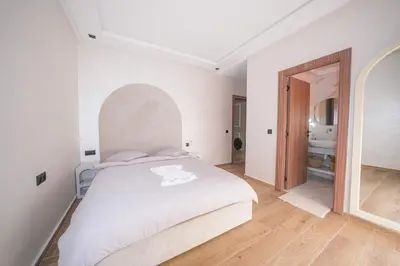 a white bedroom with a large bed and a bathroom at Modern apartments, cozy residence, swimming pools in Marrakech