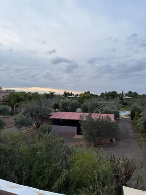a building in the middle of a field with trees at Cozy Flat , Resort-Style Pool ,10 min to Center in Marrakech