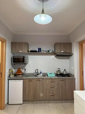 a kitchen with wooden cabinets and a microwave at Cozy Flat , Resort-Style Pool ,10 min to Center in Marrakech