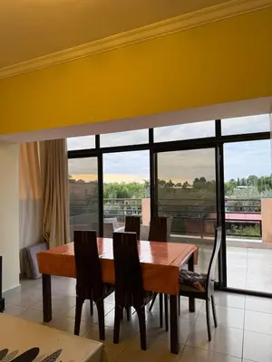 a dining room table with chairs and a large window at Cozy Flat , Resort-Style Pool ,10 min to Center in Marrakech