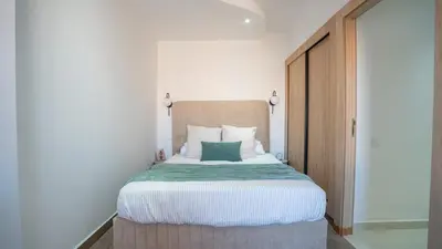 a bedroom with a bed with a green pillow on it at Appartement Chic avec Piscine au Cœur de Gueliz in Marrakech