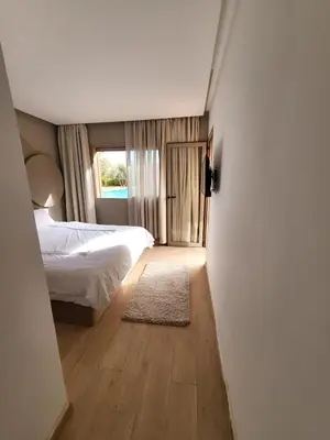 a bedroom with a bed and a window and a rug at Luxury Apartment Les Cerisiers Marrakech in Marrakech
