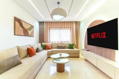 a living room with a couch and a tv at Menara Suite Harmonie , Terrasse et Piscine in Marrakech