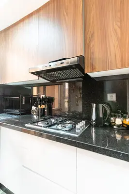 a kitchen with a stove top and wooden cabinets at Menara Suite Harmonie , Terrasse et Piscine in Marrakech