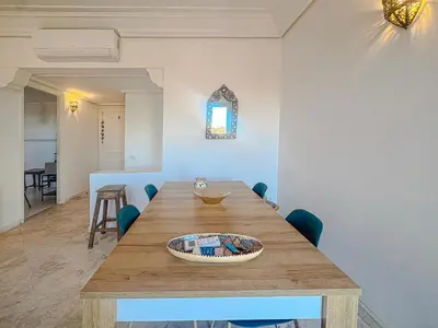 a dining room with a wooden table and chairs at Séjour Élégant et raffiné à Hivernage 2 ch & parking privé in Marrakech