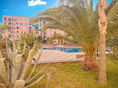 a resort with a swimming pool and palm trees at Séjour Élégant et raffiné à Hivernage 2 ch & parking privé in Marrakech