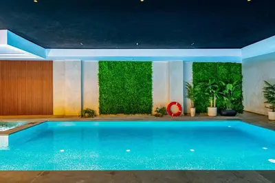 a large swimming pool with a green wall at Le Lotus - Piscine intérieur et extérieur - Wifi - Fitness in Marrakech