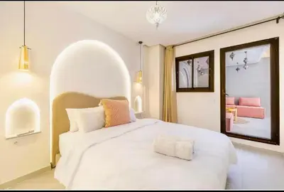 a bedroom with a large white bed and a pink couch at Simone moves to Guéliz in Marrakech