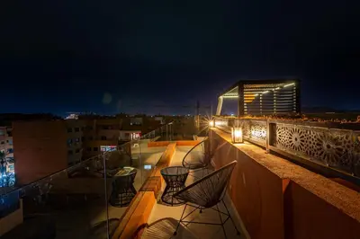 a balcony with chairs and tables at night at Private Luxury Penthouse Marrakech with Jacuzzi & Pool in Marrakech