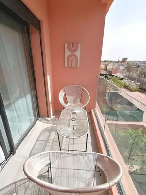 a balcony with two chairs and a table at Cosy appartement , Marrakech Noria golf in Marrakech