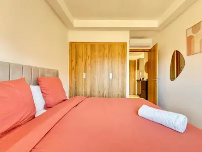 a bedroom with a large bed with orange sheets at Cosy appartement , Marrakech Noria golf in Marrakech