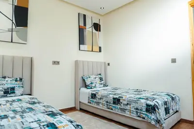 two beds in a room with white walls at Appartement moderne in Marrakech