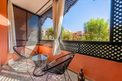 a balcony with two chairs and a window at New 2BR Apartment in Marrakech with Pools, Gym, Security & Terrace in Marrakech
