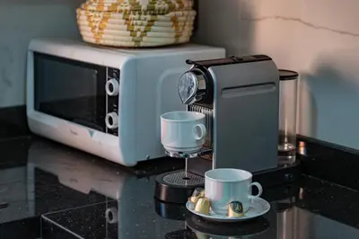 a microwave sitting on a counter with two cups at New 2BR Apartment in Marrakech with Pools, Gym, Security & Terrace in Marrakech