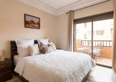 a bedroom with a white bed and a balcony at Andalous Prestige in Marrakech